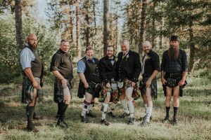 Groomsmen channeling their Scottish heritage wearing traditional kilts at an outdoor Idaho wedding in the mountains near Boise