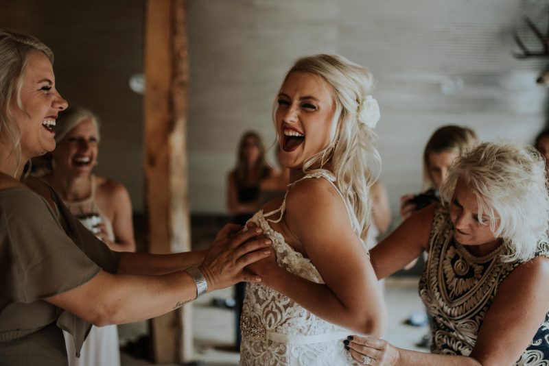 Hilarious photo of bride and her bridesmaids helping her getting ready into her wedding dress. Boise Wedding Photographer