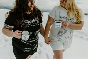 Two brides drink coffee in the snow on their wedding day in Taos New Mexico