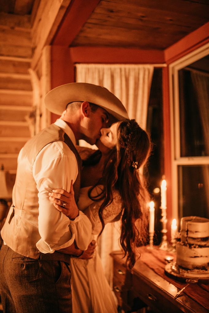 bride and groom cut their wedding cake and share a kiss at the Midnight Ranch in Steamboat Springs Colorado