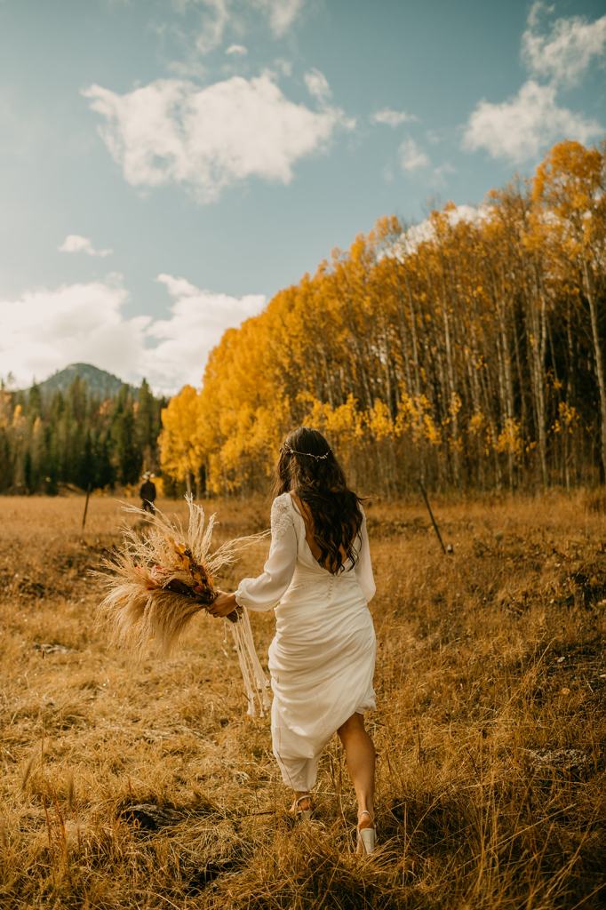 Bride walks up behind her groom for their first look on their wedding day surrounded by fall colored aspens in Steamboat Springs Colorado
