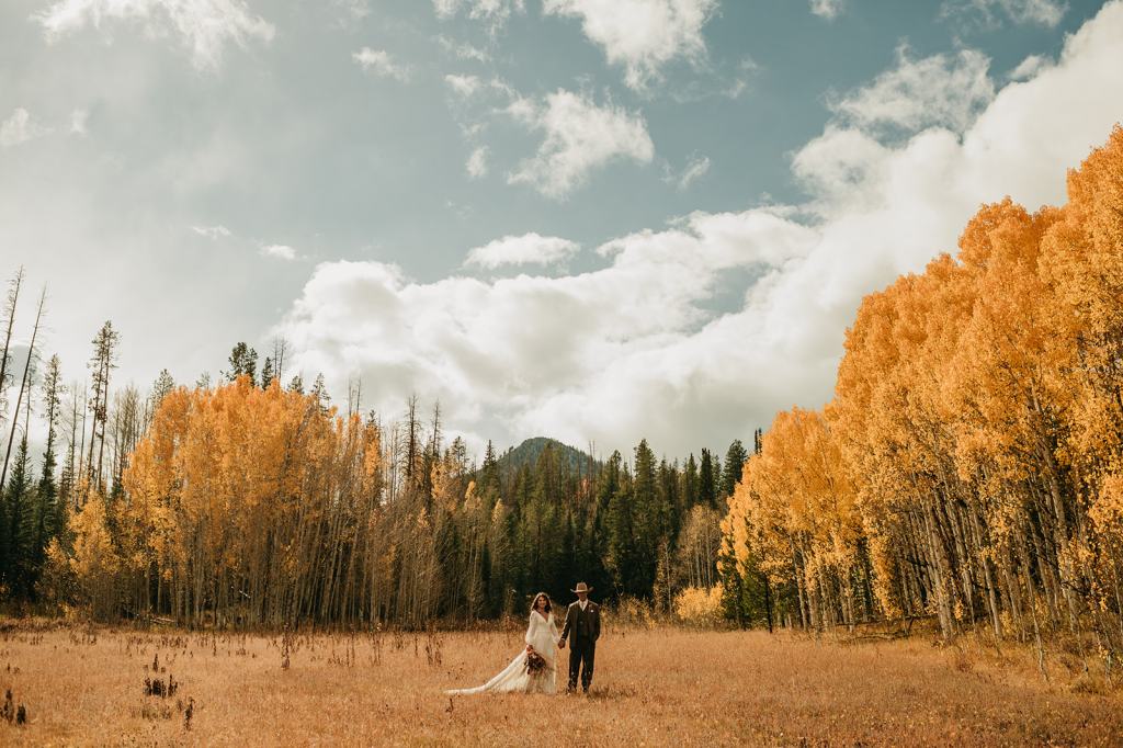 Bride and groom walk through a forest of yellow and orange aspens on their wedding day in Steamboat Springs Colorado
