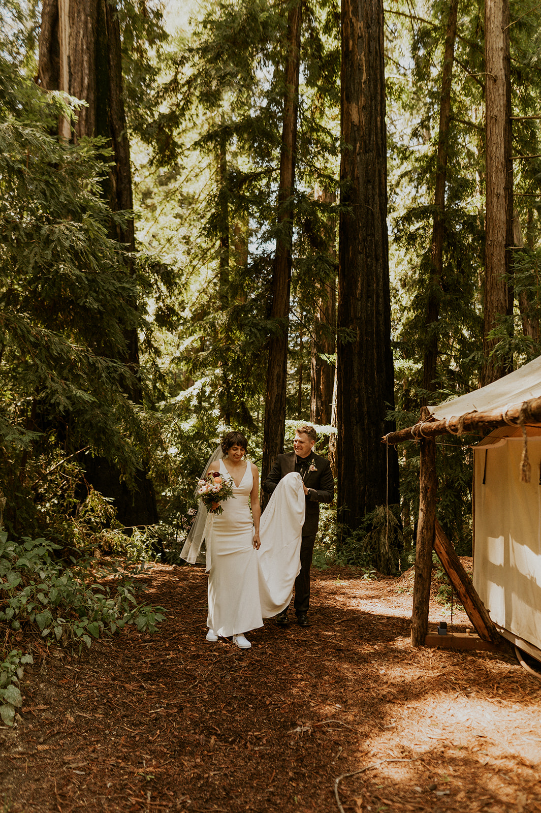Groom carries bride's wedding dress drain in the Big Sur Redwoods