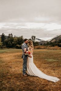 Romantic and moody fall wedding portrait of a bride and groom on their wedding day at the Sixty Chapel in Garden Valley Idaho with mountains behind them