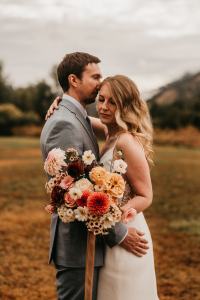 Romantic and moody fall wedding portrait of a bride and groom on their wedding day at the Sixty Chapel in Garden Valley Idaho with mountains behind them