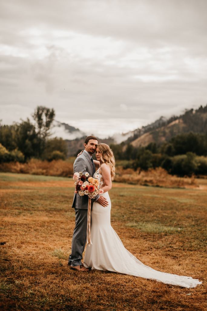 Romantic and moody fall wedding portrait of a bride and groom on their wedding day at the Sixty Chapel in Garden Valley Idaho with mountains behind them