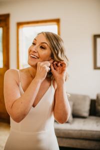 bride puts on her earrings and gets ready for her wedding day at the Sixty Chapel in Garden Valley Idaho