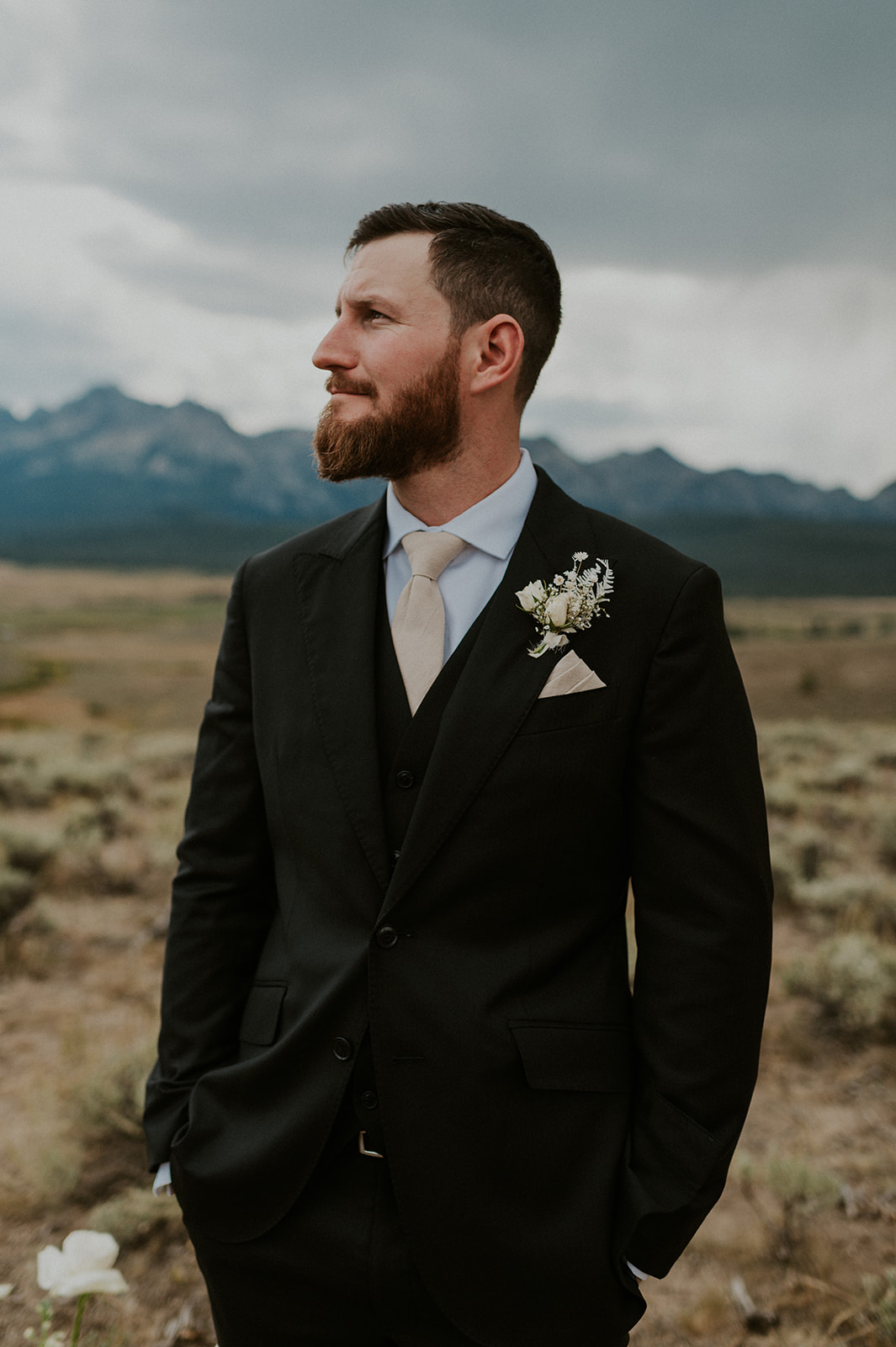 Close up detail of groom wearing an all black tux with tan accent colors and all white boutonniere 