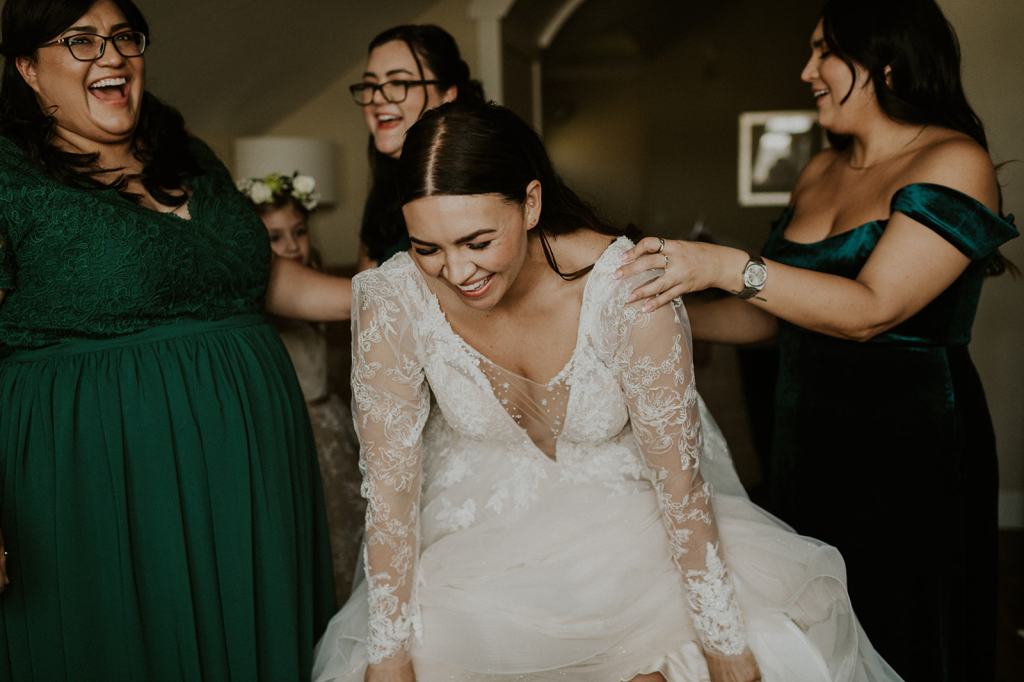 Candid moment of bride getting ready with her bridesmaids laughing