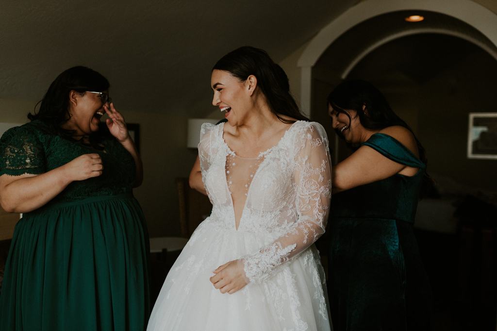 Candid moment of bride getting ready with her bridesmaids laughing