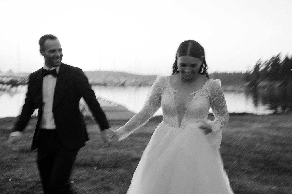 candid black and white portrait of bride and groom running 