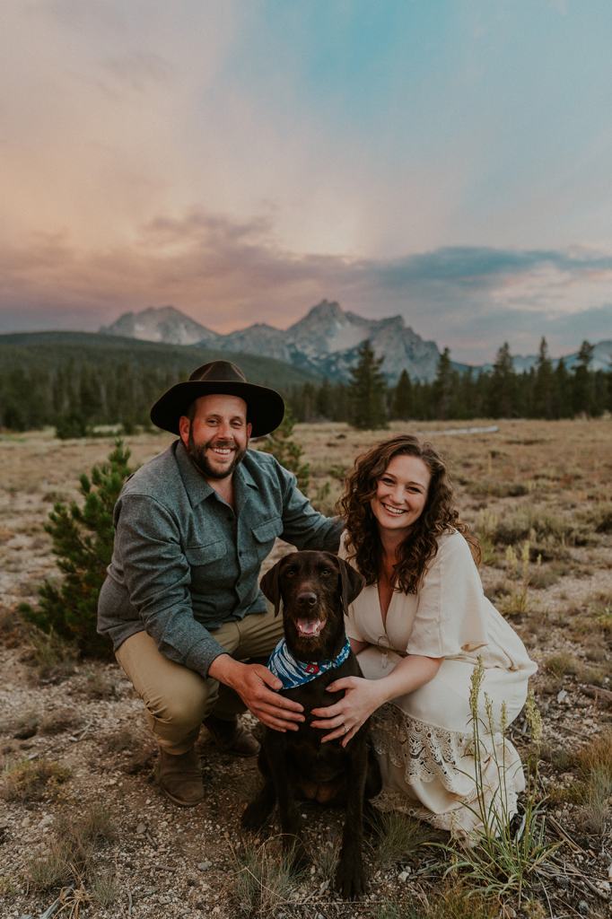Couple poses with their dog during their summer adventure engagement photos in Idaho