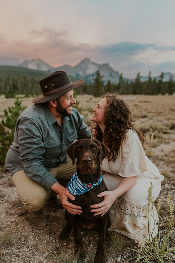 Couple poses with their dog during their summer adventure engagement photos in Idaho